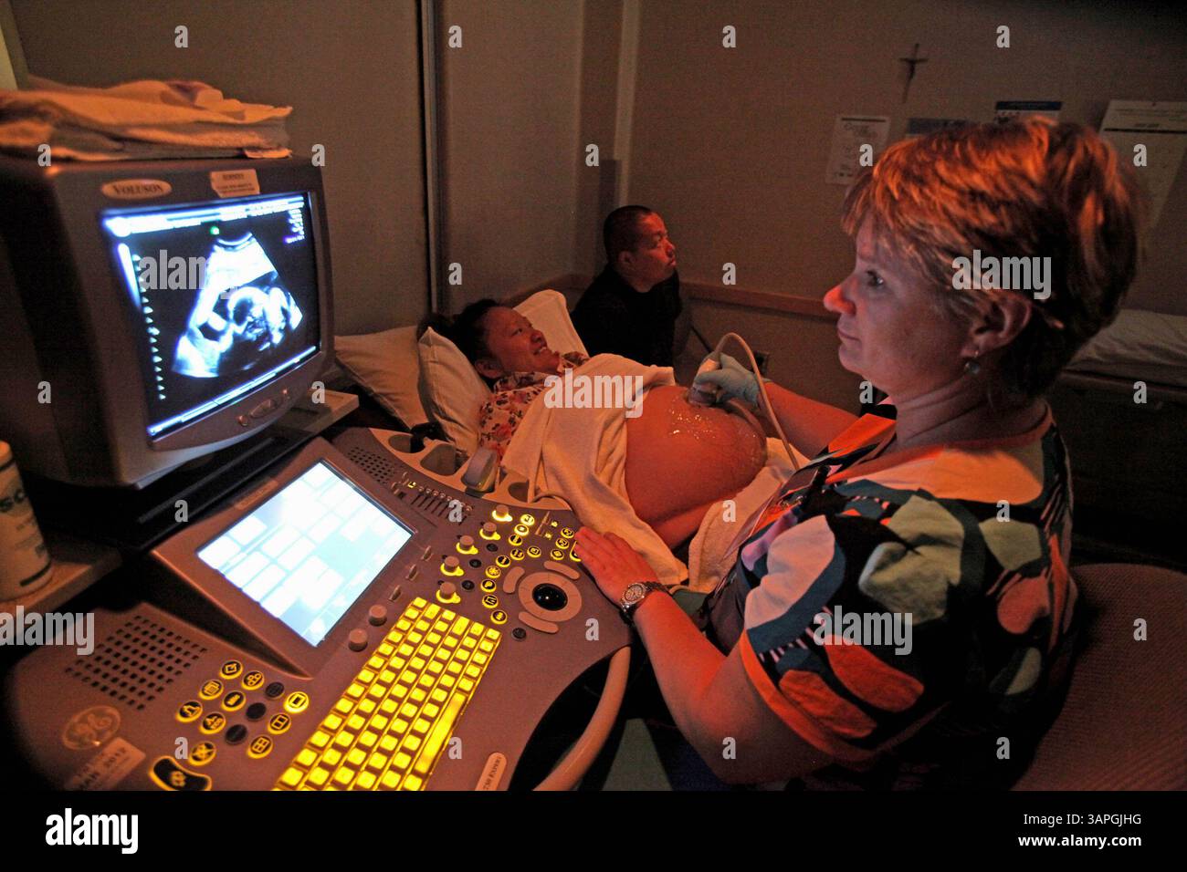 27. Juli 2011 - Milwaukee, WI, USA - Kalia Yang und ihr Freund Andy Moua, Hintergrund, sehen sich ein Ultraschallbild ihrer Zwillingsbabys an, das kürzlich von der Technikerin Rita Siudak im Vordergrund im St. Josephs Hospital durchgeführt wurde. Das Paar, das nach der Hmong-Tradition verheiratet ist, erwartet im November ihre Babys. (Bild: © Rick Wood/Milwaukee Journal Sentinel/MCT/ZUMAPRESS.com) Stockfoto