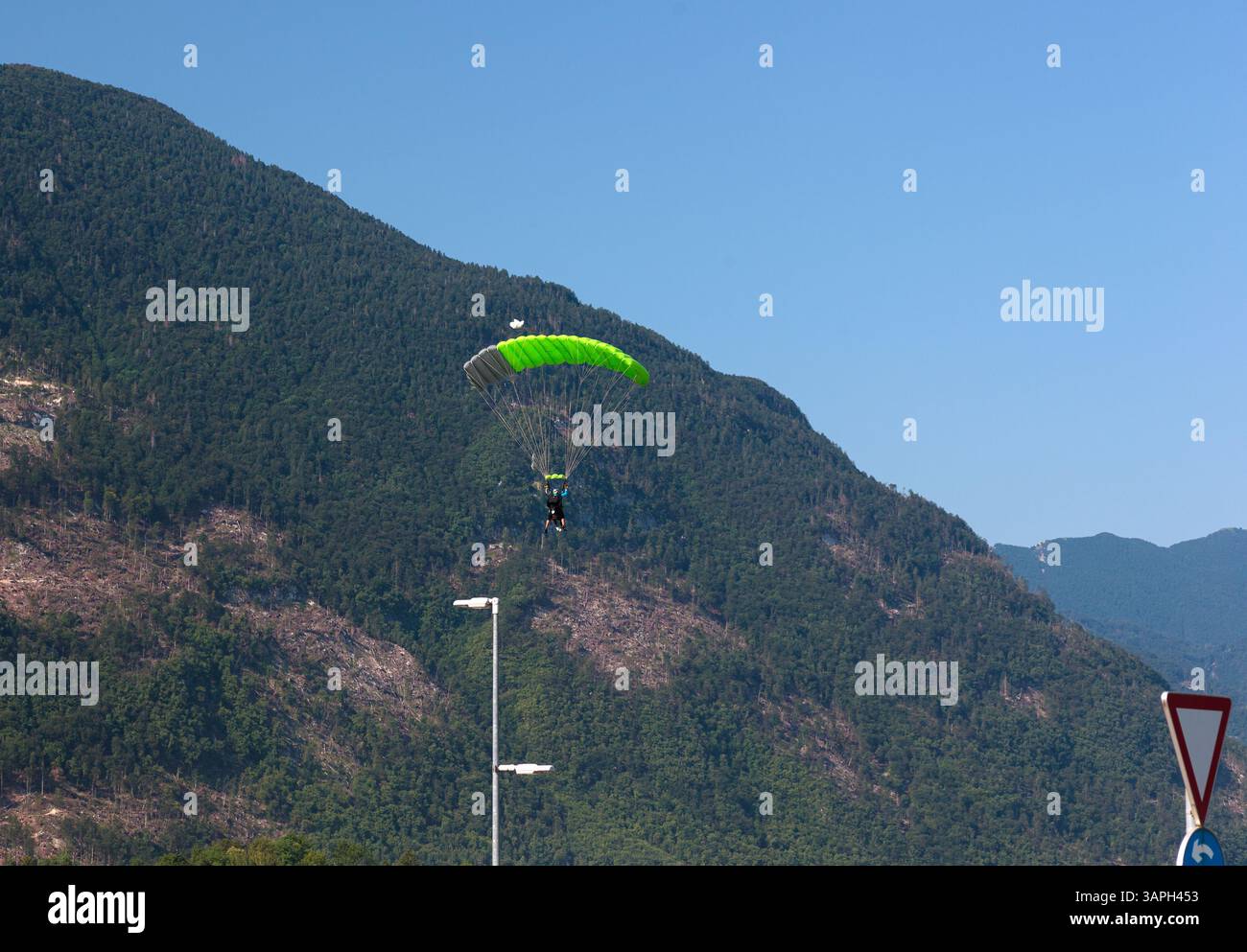 Ein Paragleiter mit rotem Fallschirm steigt nach Kanin, Slowenien, hinab, mit einer malerischen Bergkulisse im Hintergrund. Fliegen im Berg Stockfoto