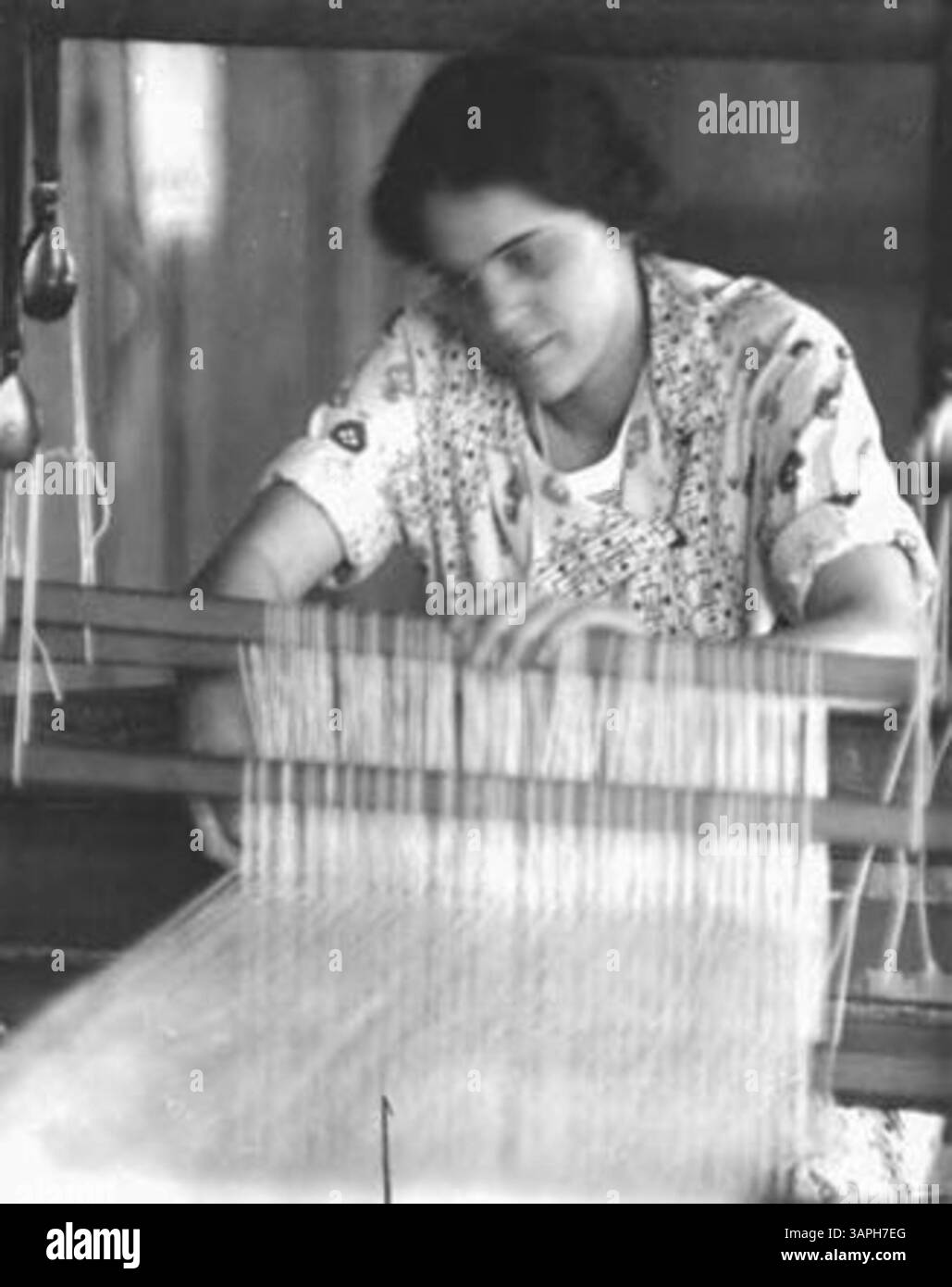 Dieses Foto zeigt Jane Chase, eine Spinnerin und Weberin, die am Webstuhl arbeitet. Es ist Teil einer historischen Sammlung, die traditionelles Kunsthandwerk des frühen 20. Jahrhunderts zeigt. Stockfoto