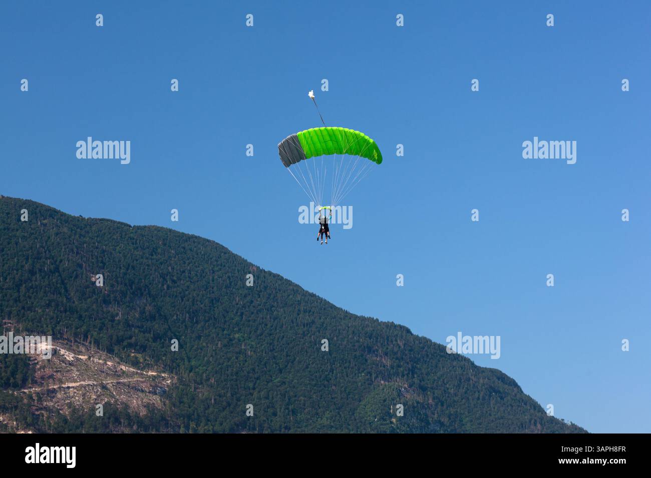 Ein Paragleiter mit rotem Fallschirm steigt nach Kanin, Slowenien, hinab, mit einer malerischen Bergkulisse im Hintergrund. Fliegen im Berg Stockfoto