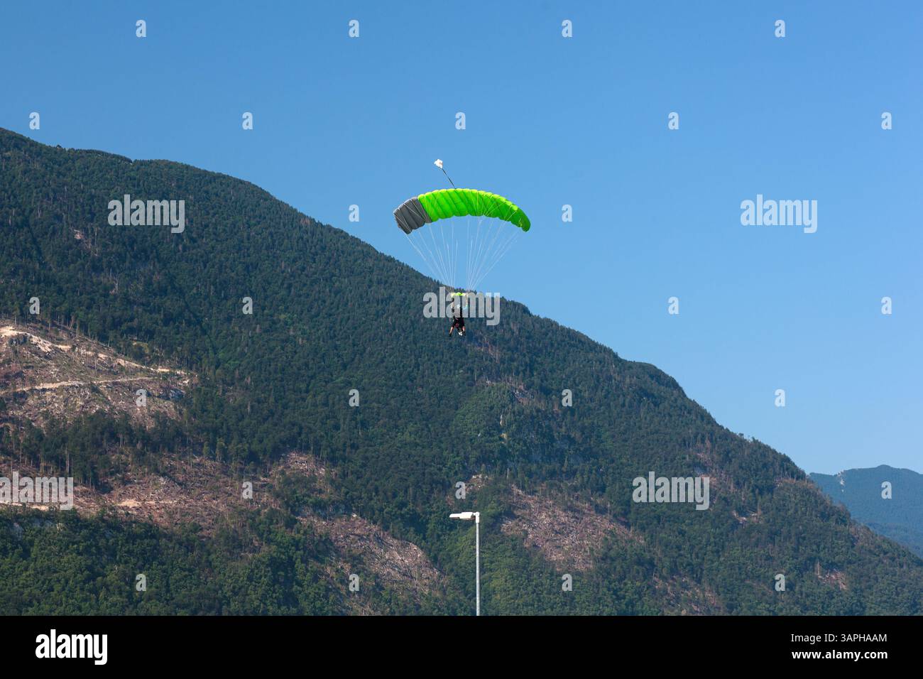 Ein Paragleiter mit rotem Fallschirm steigt nach Kanin, Slowenien, hinab, mit einer malerischen Bergkulisse im Hintergrund. Fliegen im Berg Stockfoto