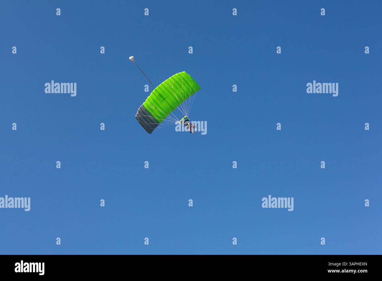 Ein Gleitschirm mit grünem Fallschirm fährt hinunter nach Kanin, Slowenien, mit blauem Himmel im Hintergrund. Stockfoto
