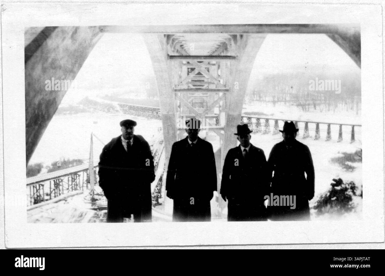 Das Foto zeigt vier Männer, die auf einer der Stützen der Mendota-Brücke im Bau posieren. Sie stehen auf den Bogenrippen und demonstrieren die Höhe und die gefährliche Arbeit, die beim Bau dieser Wahrzeichen-Brücke erforderlich ist. Stockfoto