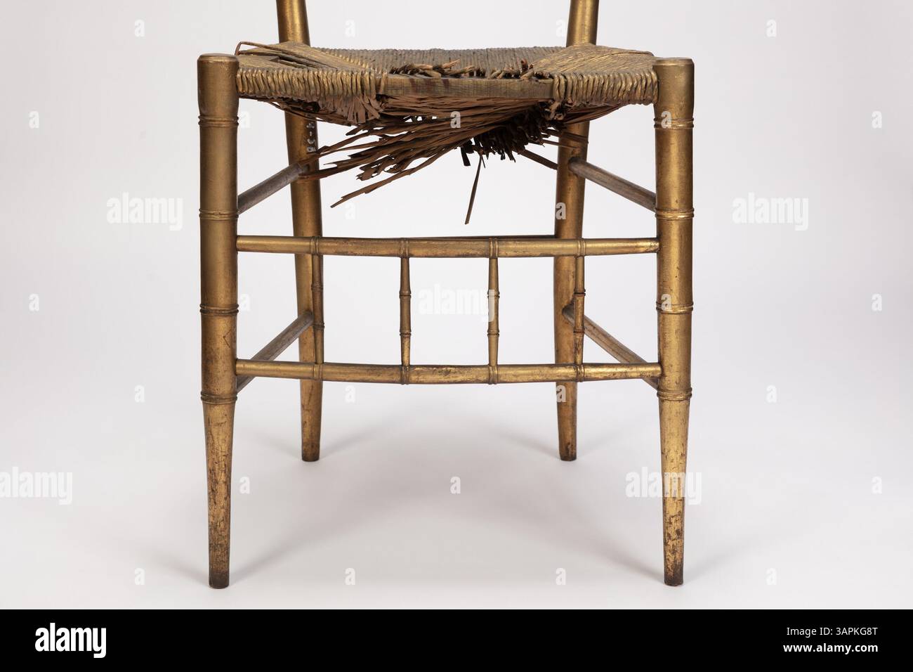 Ein hlzerner Beistellstuhl im Chiavari-Stil, goldgestrichen, mit einem  Rush-Sitz und Bambus-gedrehten Schienen. Chiavari Sthle, bekannt fr ihr  leichtes und elegantes Design, wurden im 19. Jahrhundert in den USA in  formellen Umgebungen weit