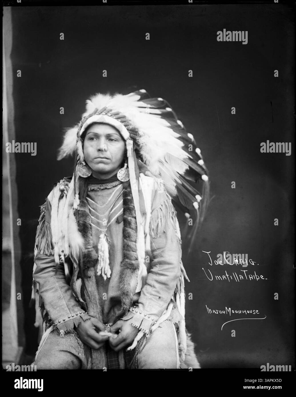 Foto von Lee Moorhouse mit Joe Craig, einem Umatilla-Indianer, der eine Kriegshaube trägt. Das Bild zeigt eine traditionelle kulturelle Darstellung, die das Erbe und die Kleidung der amerikanischen Ureinwohner widerspiegelt. Stockfoto