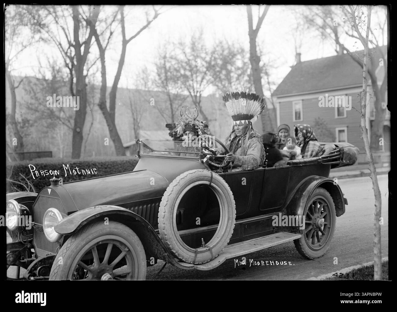 Ein Seitenblick auf Motanic und seine Familie in ihrem neuen Hudson-Auto, eines der ersten auf ihrer Reservierung. Motanic trägt einen Federkopf, der das kulturelle Erbe symbolisiert. Stockfoto