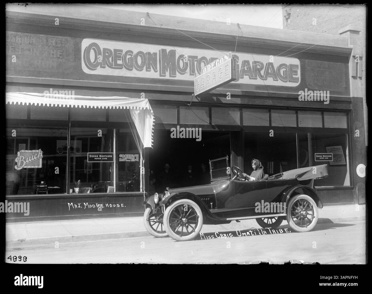 Dieses Foto von Lee Moorhouse zeigt Miss Craig, eine Stammesfrau der Umatilla, hinter dem Steuer einer 1910er Buick Limousine vor der Oregon Motor Garage in Pendleton, Oregon. Es spiegelt die Schnittstelle von indigener Kultur und amerikanischer Automobilgeschichte des frühen 20. Jahrhunderts wider. Stockfoto