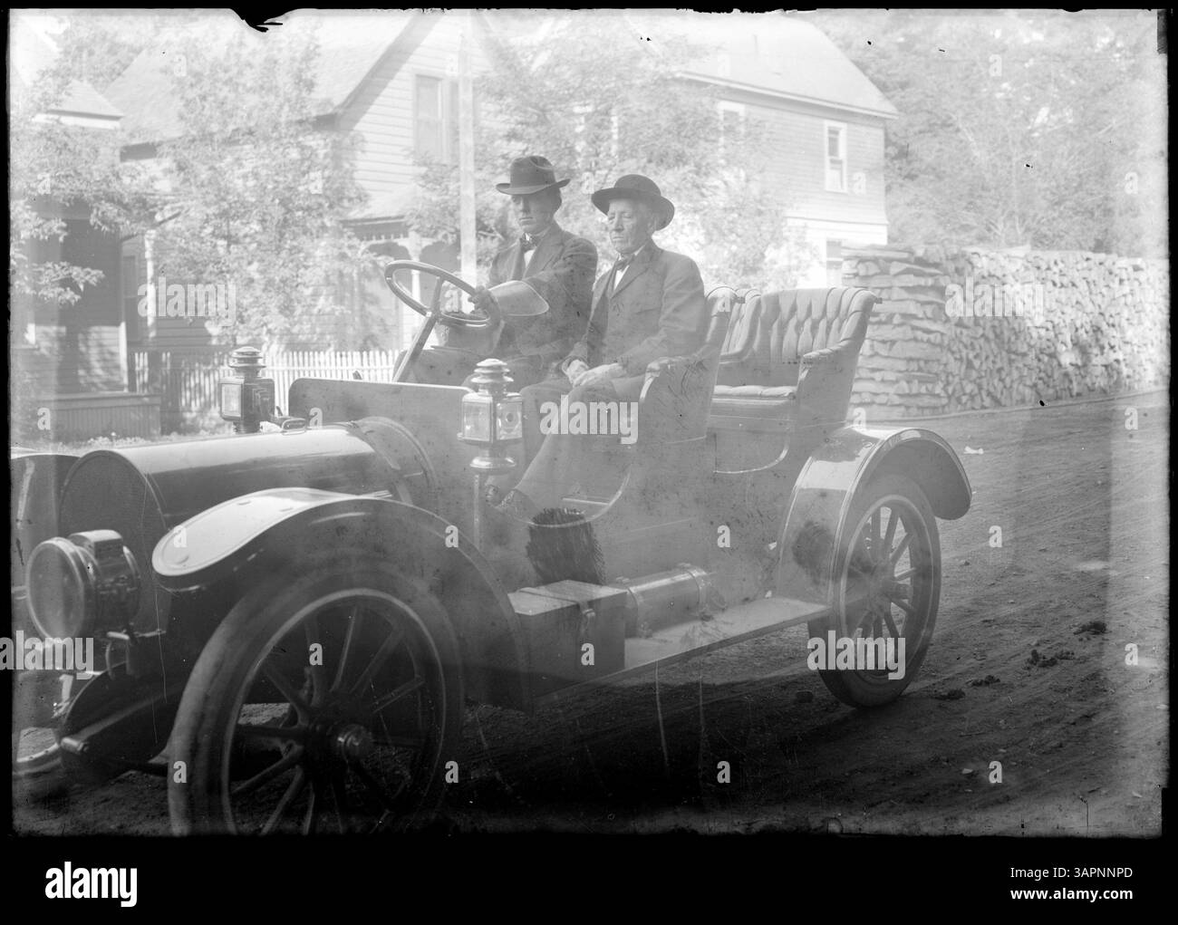 Lee Moorhouse fotografiert eine Autoparade in Pendleton, Oregon, auf der zwei Männer in einem Auto vor einem Haus gezeigt werden, die das Ereignis des frühen 20. Jahrhunderts dokumentieren. Stockfoto