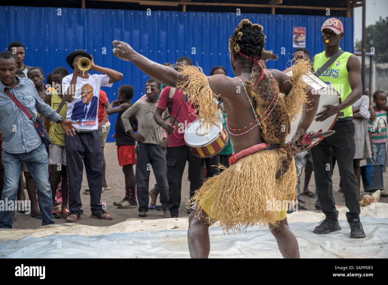 Kongolesische Wrestling-Kämpfer ziehen durch die Straßen eines Kinshasa-Vorortes auf dem Weg zu einem provisorischen Ring für ein Spiel, während eine lokale Band folgt Stockfoto