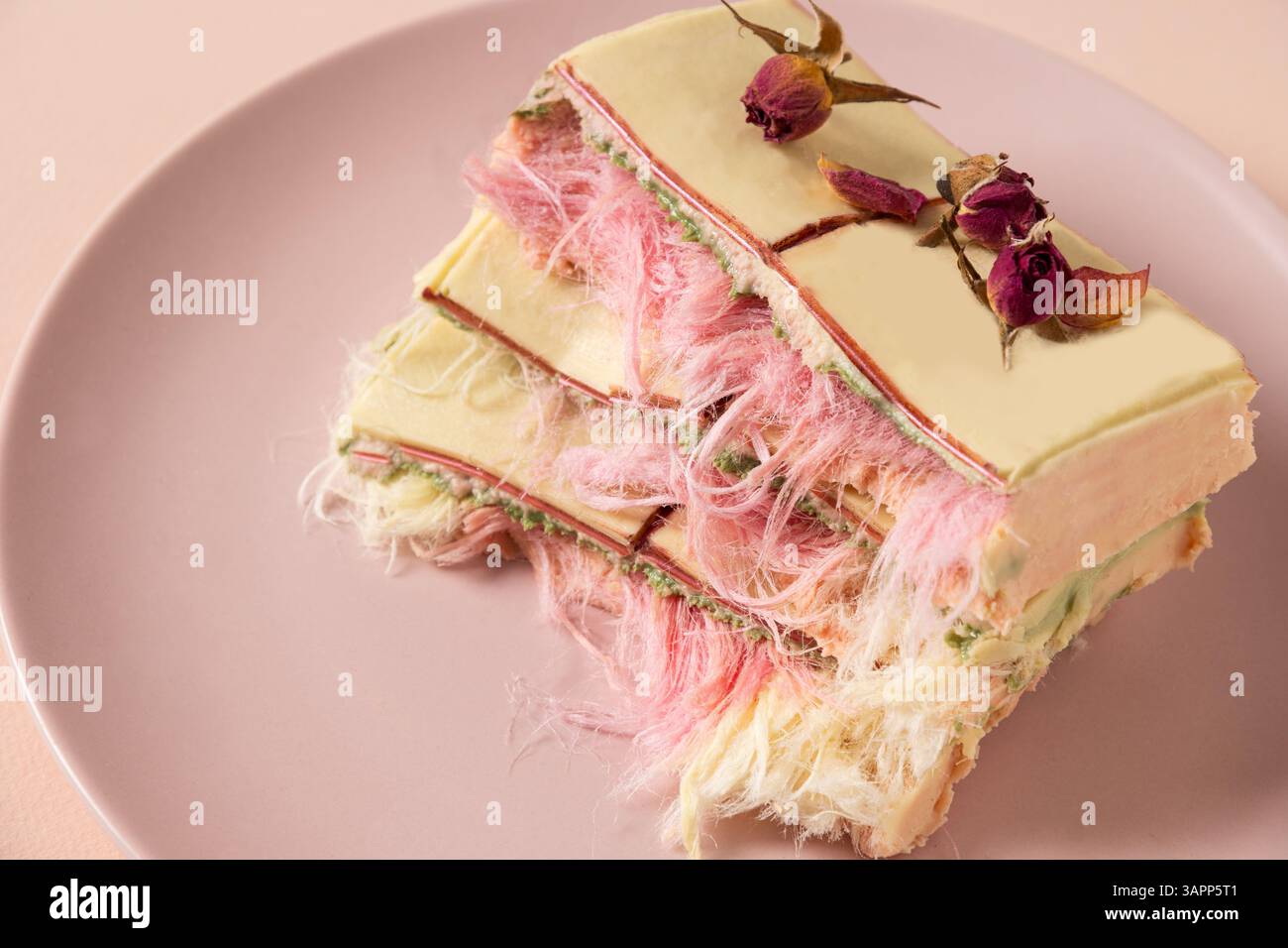 Trendige weiße, rosafarbene Schokolade mit Schicht aus weißem und rosafarbenem Pismaniye auf rosa Hintergrund. Leckeres Dessert mit Zuckerwatte. Luxuriöses Dessert. Nahaufnahme. Stockfoto