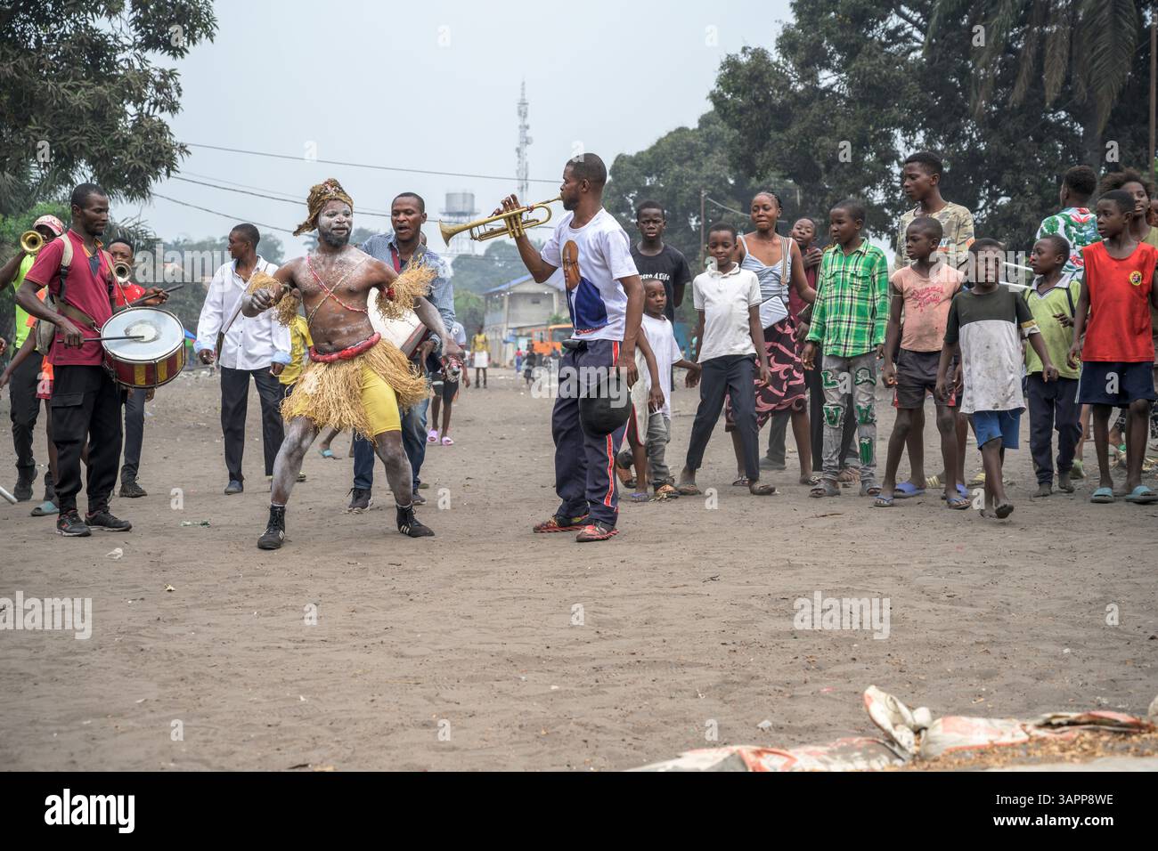 Kongolesische Wrestling-Kämpfer ziehen durch die Straßen eines Kinshasa-Vorortes auf dem Weg zu einem provisorischen Ring für ein Spiel, während eine lokale Band folgt Stockfoto