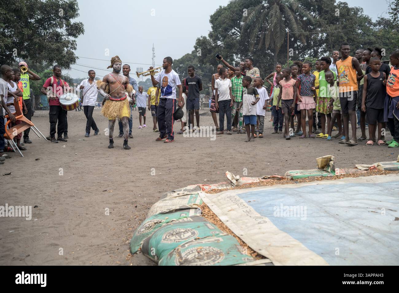 Kongolesische Wrestling-Kämpfer ziehen durch die Straßen eines Kinshasa-Vorortes auf dem Weg zu einem provisorischen Ring für ein Spiel, während eine lokale Band folgt Stockfoto