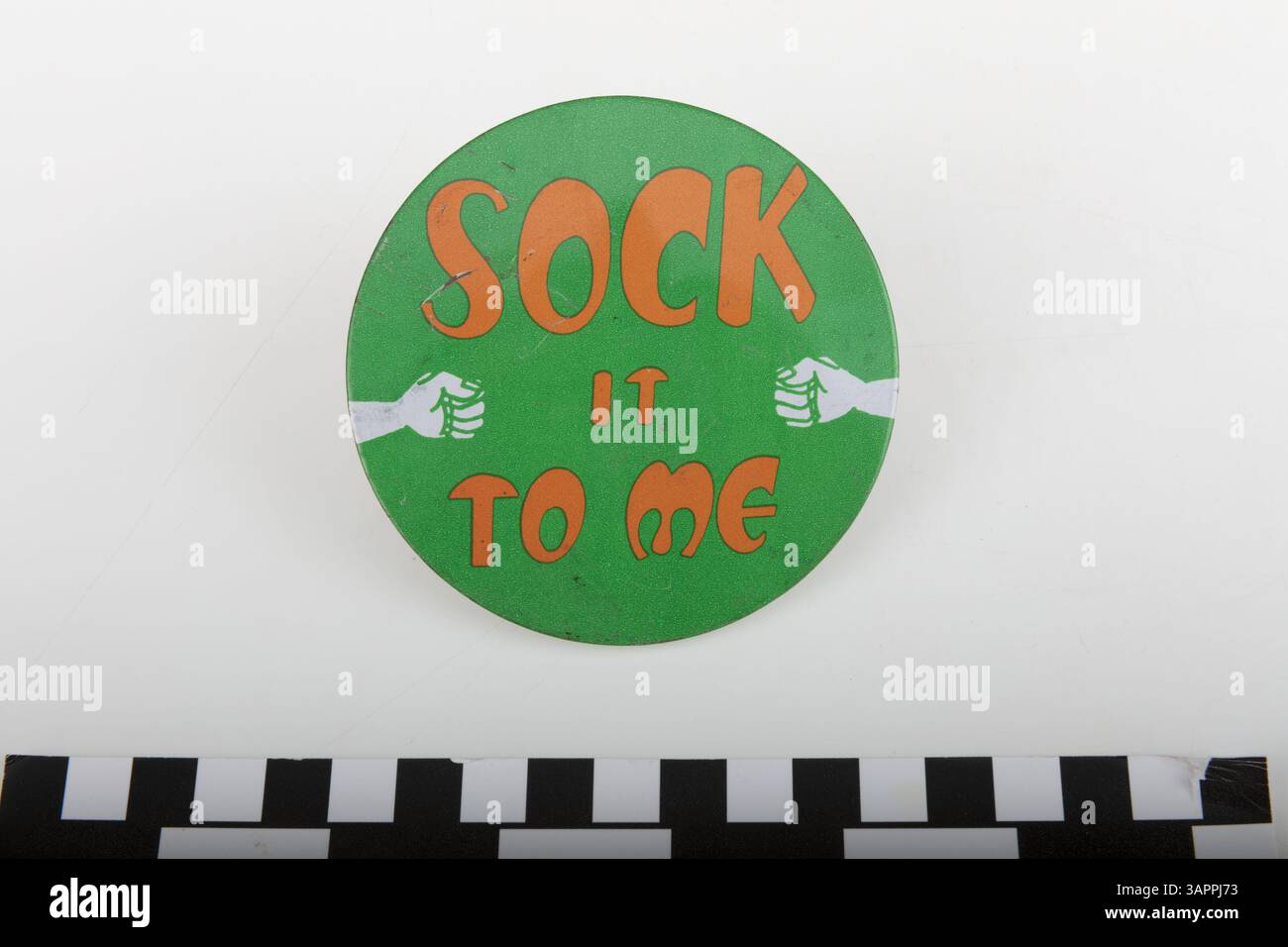 Der Sock IT To Me Button wurde von Mitgliedern der Welders getragen, einer der ersten Punkbands von St. Louis, die von 1975 bis 1981 aktiv waren. Die Band bestand aus sieben Frauen, darunter Stephanie von Drasek, Jane Fujimoto, Kelly 'Rusty' Draper, Caroline Fujimoto, Colleen Cowan O'Sullivan, Lyla Turner und Julie Benz. Der Button ist ein Symbol für den frühen Einfluss der Band in der Punkszene. Stockfoto