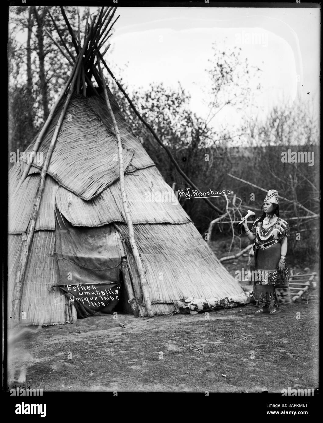 Foto von Lee Moorhouse von Esther Umahollis, einer Stammesfrau der Umpqua, in traditionellen Insignien, die an einem Tipi stehen. Das Bild zeigt die kulturelle Kleidung der amerikanischen Ureinwohner und die Traditionen der Stammesstämme. Stockfoto