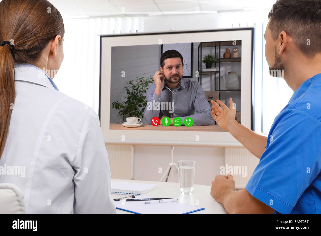 Redner, der über Online-Videochat an der Vorlesung teilnimmt. Medizinisches Personal im Konferenzraum mit Projektionsleinwand Stockfoto