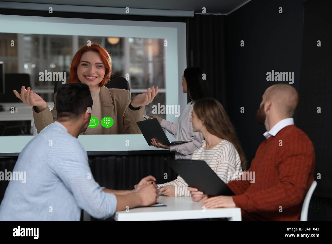 Redner, der über Online-Videochat an der Vorlesung teilnimmt. Publikum und Trainer im Konferenzraum mit Projektionsleinwand Stockfoto