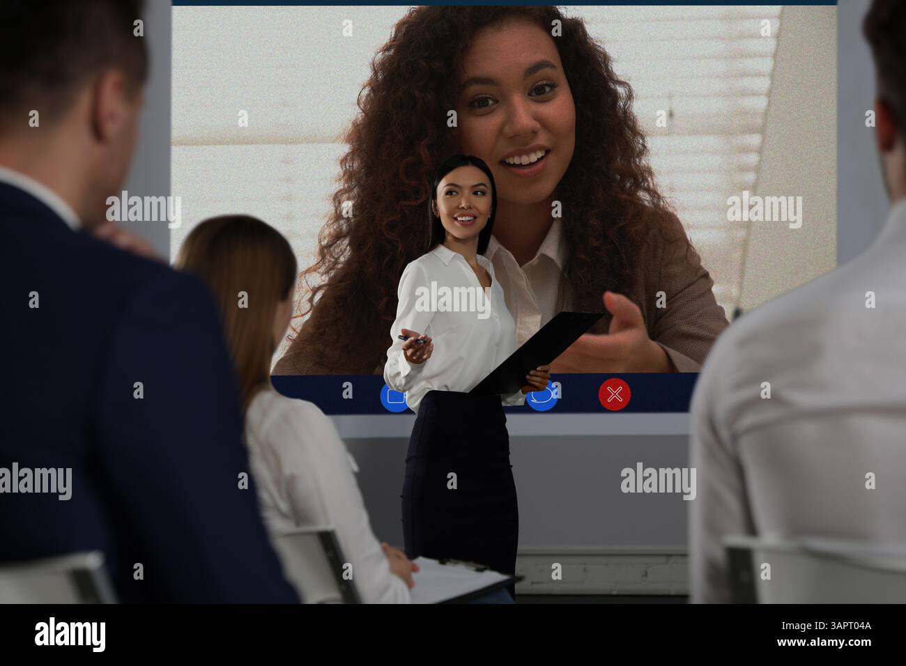 Redner, der über Online-Videochat an der Vorlesung teilnimmt. Publikum und Trainer im Konferenzraum mit Projektionsleinwand Stockfoto