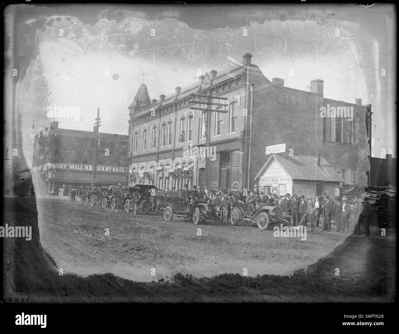 Foto von Lee Moorhouse, das eine Reihe von Autos vor dem Büro des Stadtmarschalls und Spoonmores Arbeitsamt in Pendleton, Oregon, zeigt. Dieses Bild zeigt den Alltag und die frühe Automobilkultur in Pendleton. Stockfoto