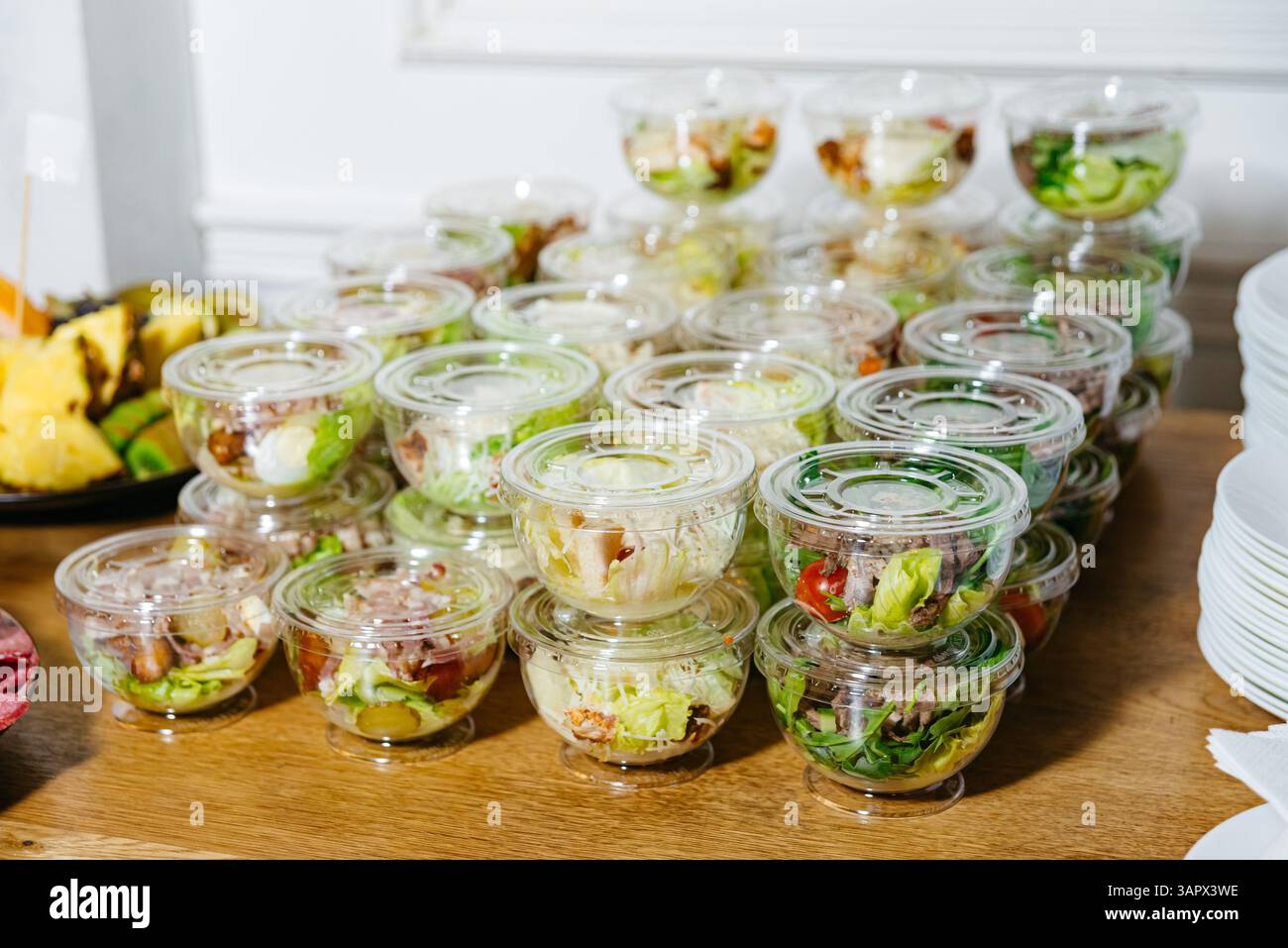 Mehrere durchsichtige, mit frischem Gemüse gefüllte Salatschüsseln aus Kunststoff, die ordentlich gestapelt sind, um sie bei einer Veranstaltung oder einem Buffet mit Catering zu servieren. Stockfoto