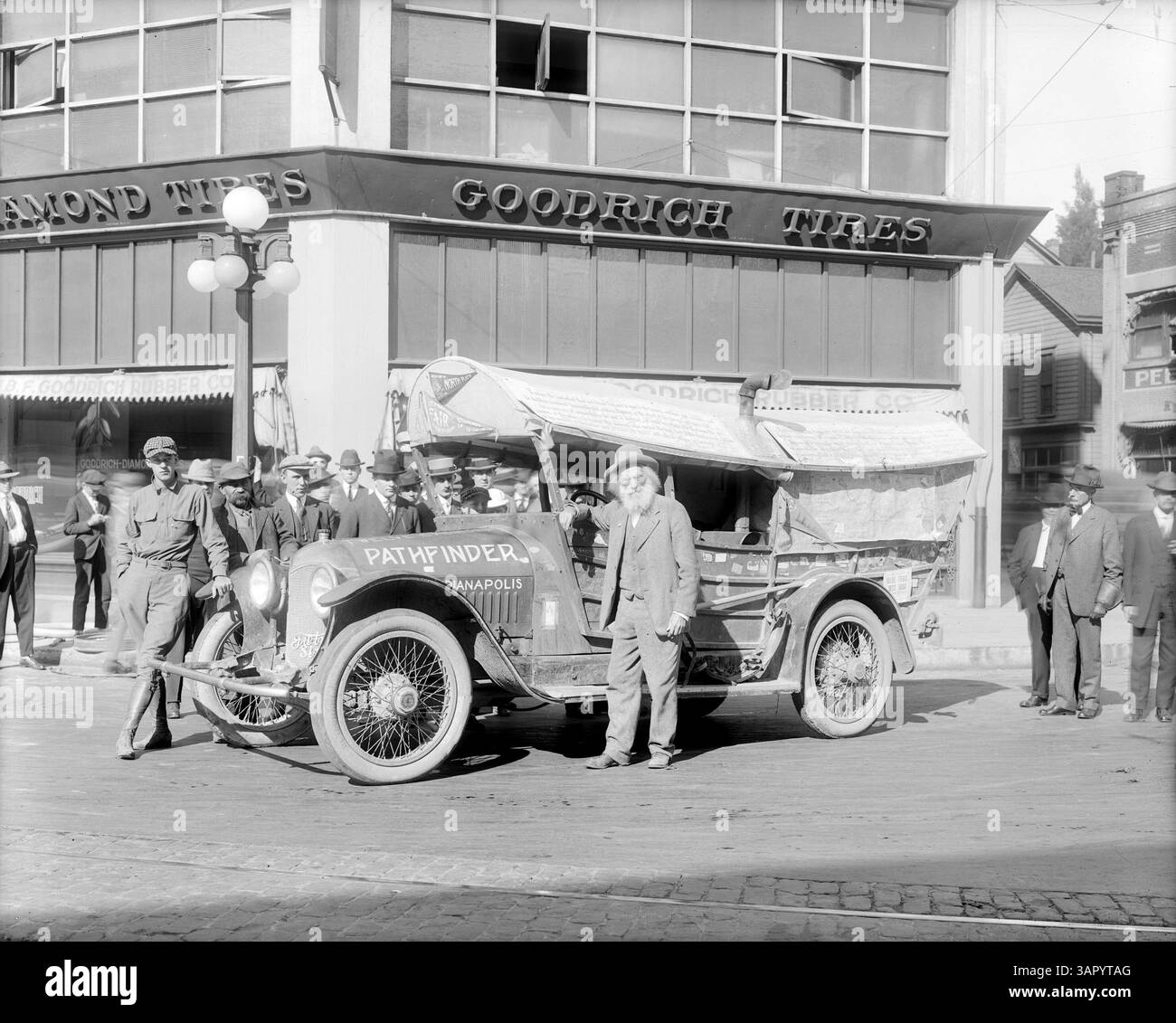 Dieses Foto von Angelus Studio zeigt Ezra Meeker neben dem Schoner-Mobil, ein Auto mit einem Leinendach, das wie ein Wagenzug gestaltet ist. Das Bild zeigt ein ikonisches Stück amerikanischer Geschichte und Transportentwicklung im frühen 20. Jahrhundert. Stockfoto