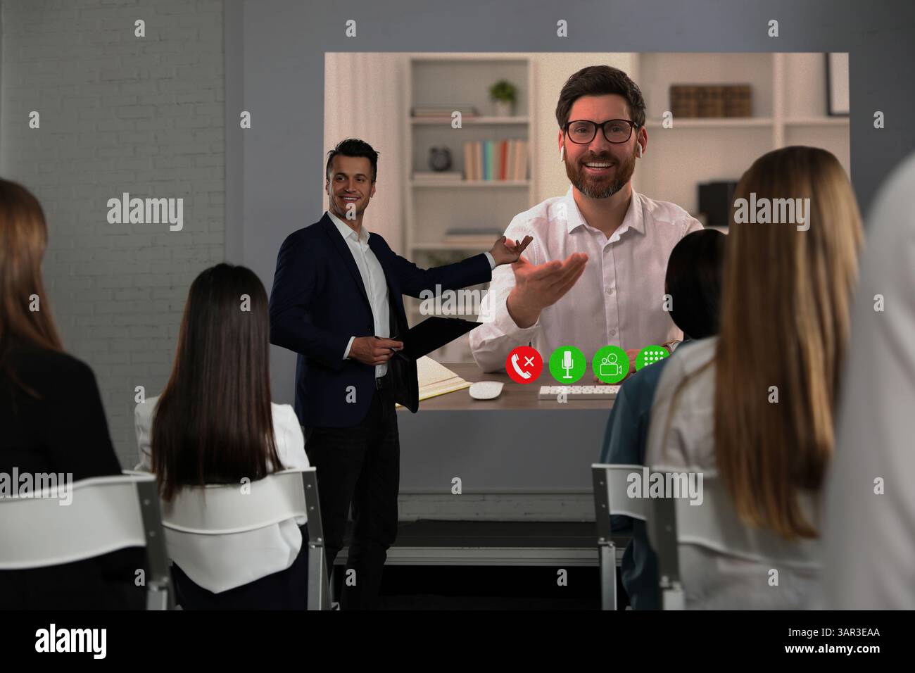 Redner, der über Online-Videochat an der Vorlesung teilnimmt. Publikum und Trainer im Konferenzraum mit Projektionsleinwand Stockfoto