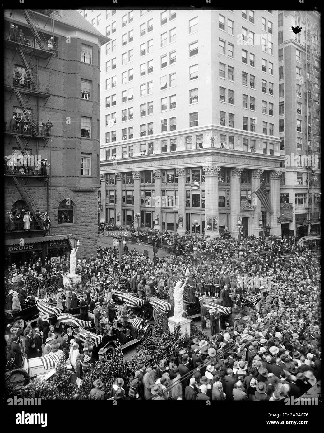 Ein Foto aus der Angelus Studio-Sammlung der University of Oregon Libraries, das die Freiheitskreditveranstaltung von 1918 in SW 6th und Morrison in Portland dokumentiert. Das Bild zeigt mit Fahnen überzogene Autos, Freiheitsstatuen und Banner, die die Unterstützung der Bemühungen des Ersten Weltkriegs fördern. Stockfoto