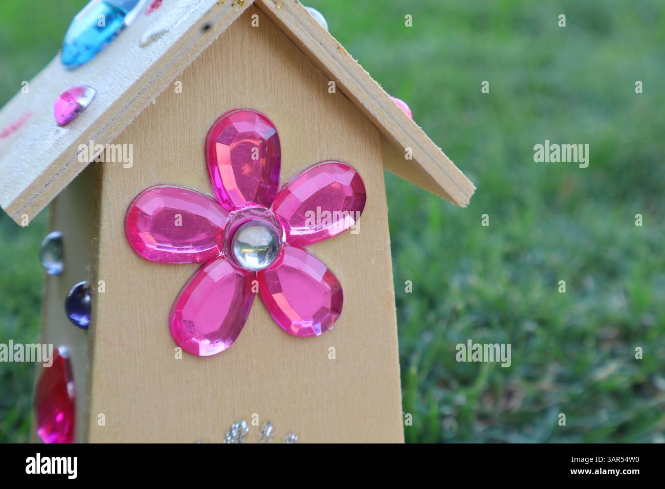 Kinderhandwerkshaus mit bunten Juwelen und Gras im Hintergrund, das jede Fee lieben würde Stockfoto