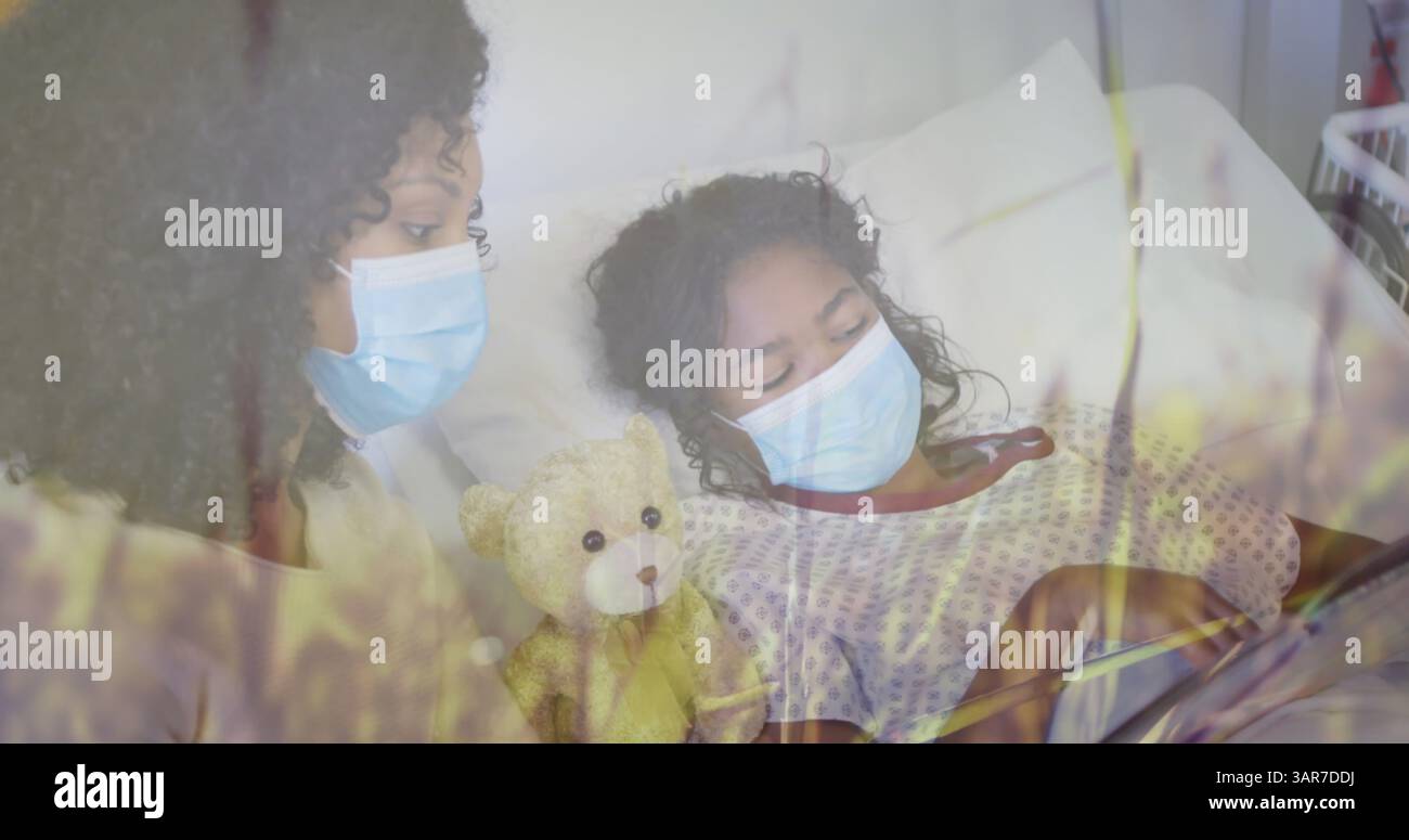 Grasbild über birassischer Mutter mit Gesichtsmasken und ihrer im Krankenhaus liegenden Tochter Stockfoto