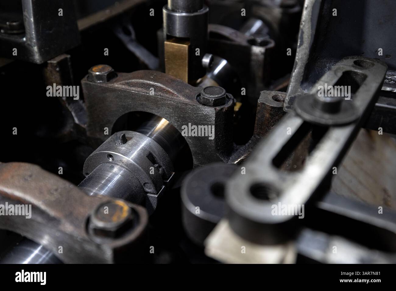 Ein Mechaniker verwendet eine Spezialmaschine, um das Nockenwellenbett eines Zylinderkopfs in einer Werkstatteinstellung wiederherzustellen. Stockfoto