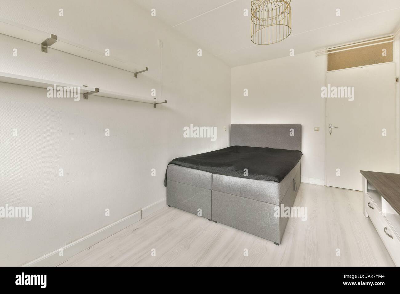 Ein schlichtes und modernes Schlafzimmer mit einem eleganten schwarzen Bett und Wänden in neutralen Farbtönen für eine minimalistische Ästhetik. Stockfoto