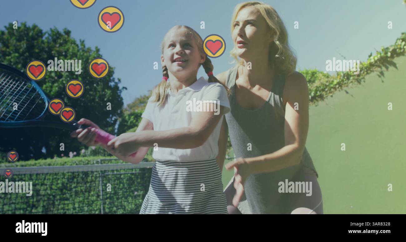 Bild von Herzsymbolen über der kaukasischen Mutter mit Tochter, die Tennis spielt Stockfoto