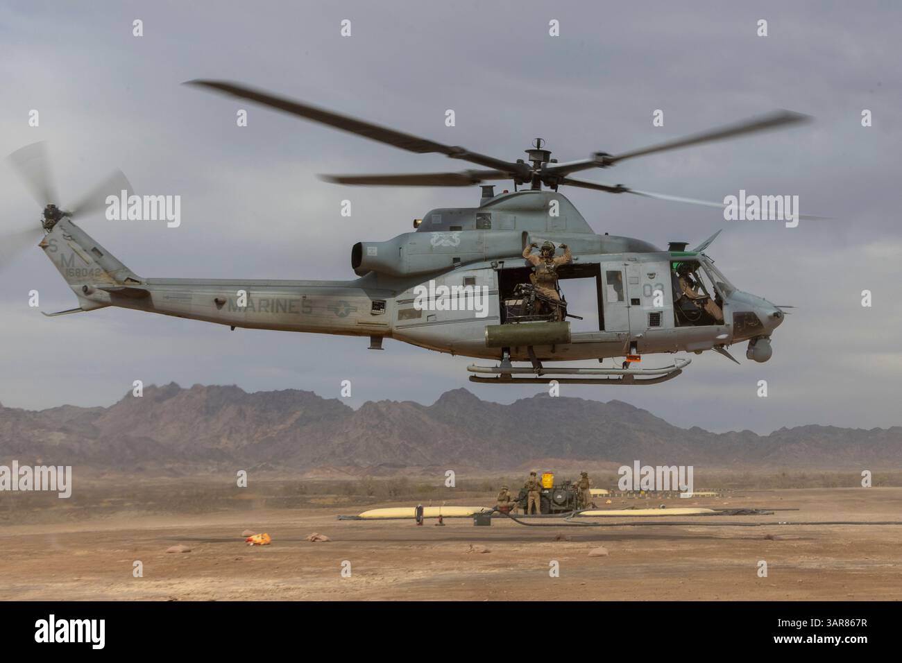 Ein US-Marine, der der Marine Aviation Weapons and Tactics Squadron One (MAWTS-1) zugeteilt ist, führt den Gruß des Kanonenkämpfers in einem UH-1Y-Gift auf einem Forward A aus Stockfoto