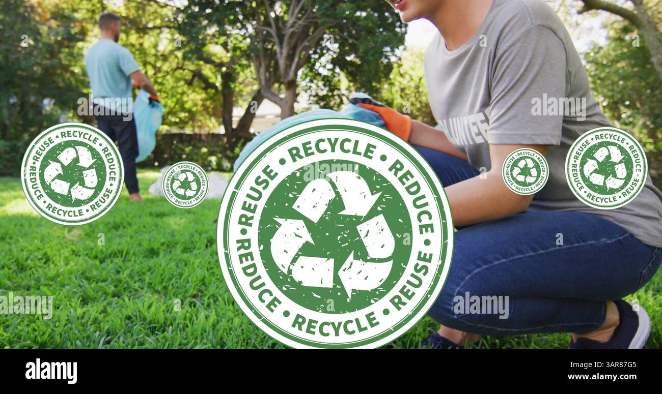 Bild von Recycling-Symbolen über lächelnden Freiwilligen, die den Garten reinigen Stockfoto