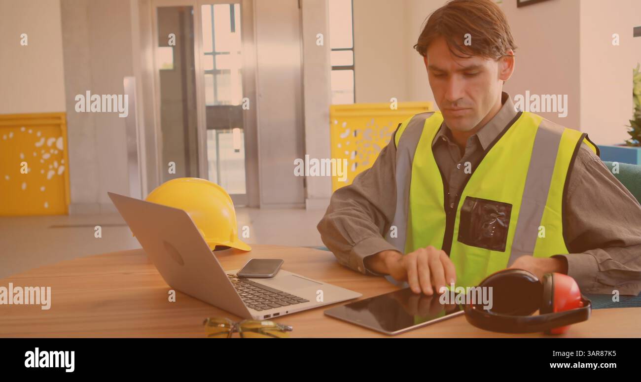 Bild eines kaukasischen Arbeiters mit Laptop und Tablet im Büro Stockfoto