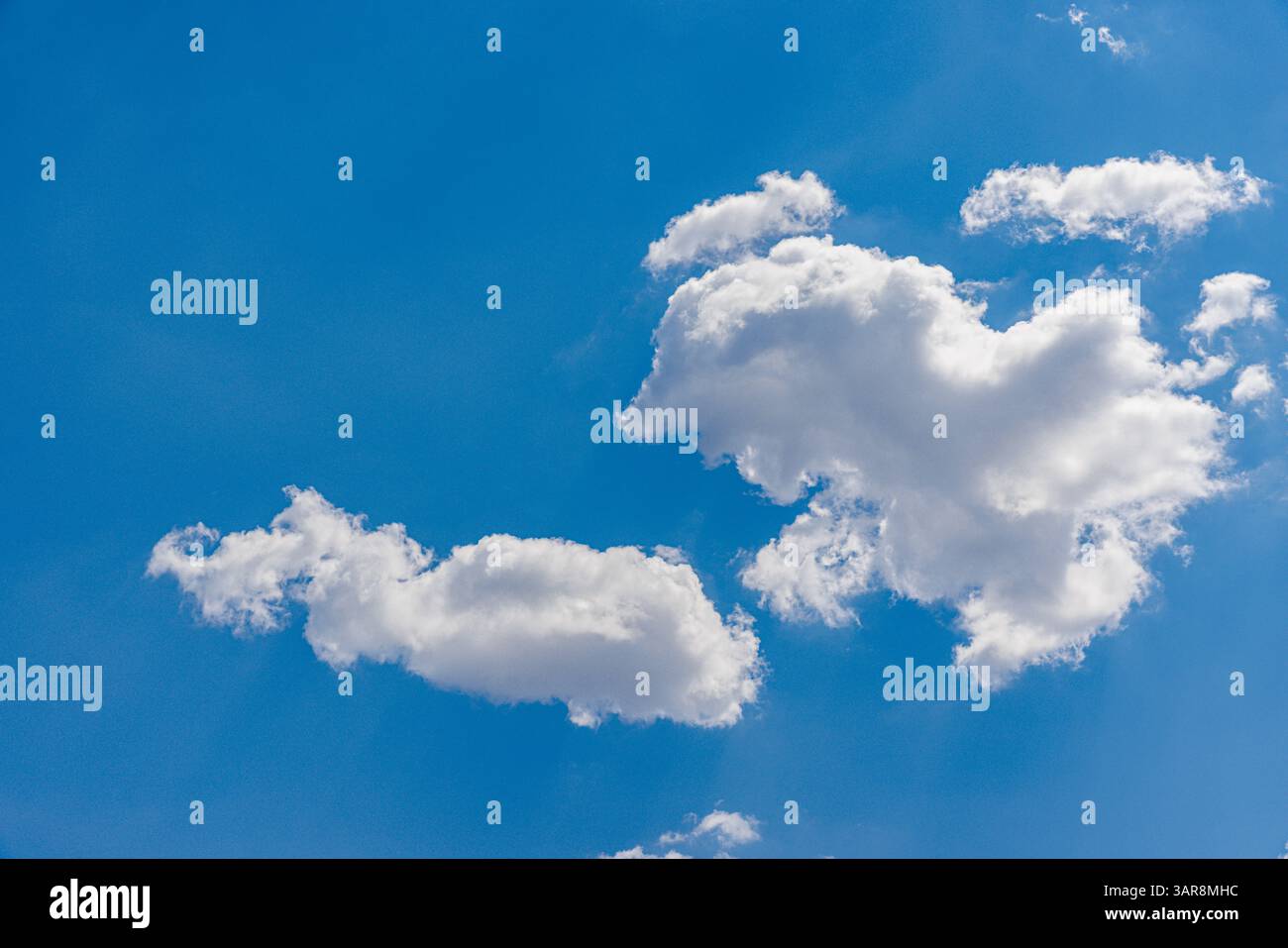 Sonniger Tag mit klarem blauem Himmel und weichen weißen Wolken, perfekt für friedliche Naturszenen, Outdoor-Hintergründe und helles Sommerwetter-Inspiration Stockfoto
