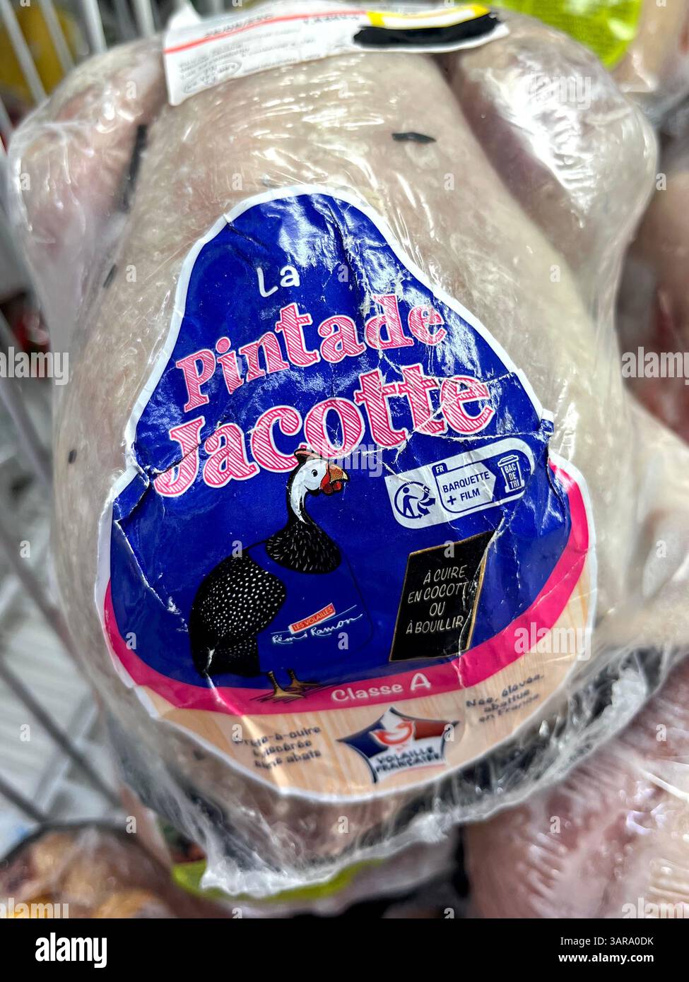 Abgepacktes Fleisch von Jacotte-Perlhühnern (Pintade) in einem Tiefkühlschrank im Supermarkt, fertig für den Einzelverkauf als gefrorenes Gourmet-Geflügelerzeugnis. Stockfoto