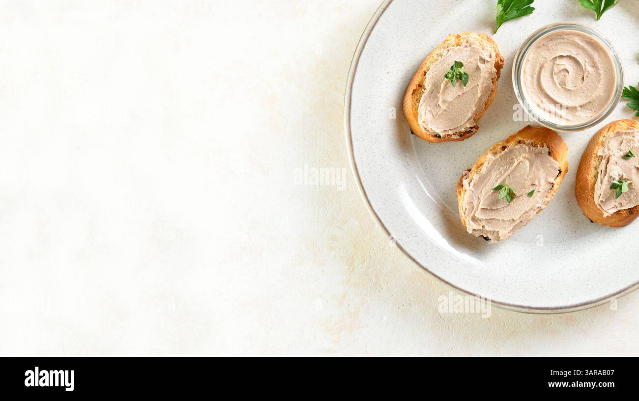 Nahansicht der Hühnerleberpastete auf geröstetem Brot auf Teller über hellem Hintergrund mit Kopierraum. Draufsicht, flach Stockfoto