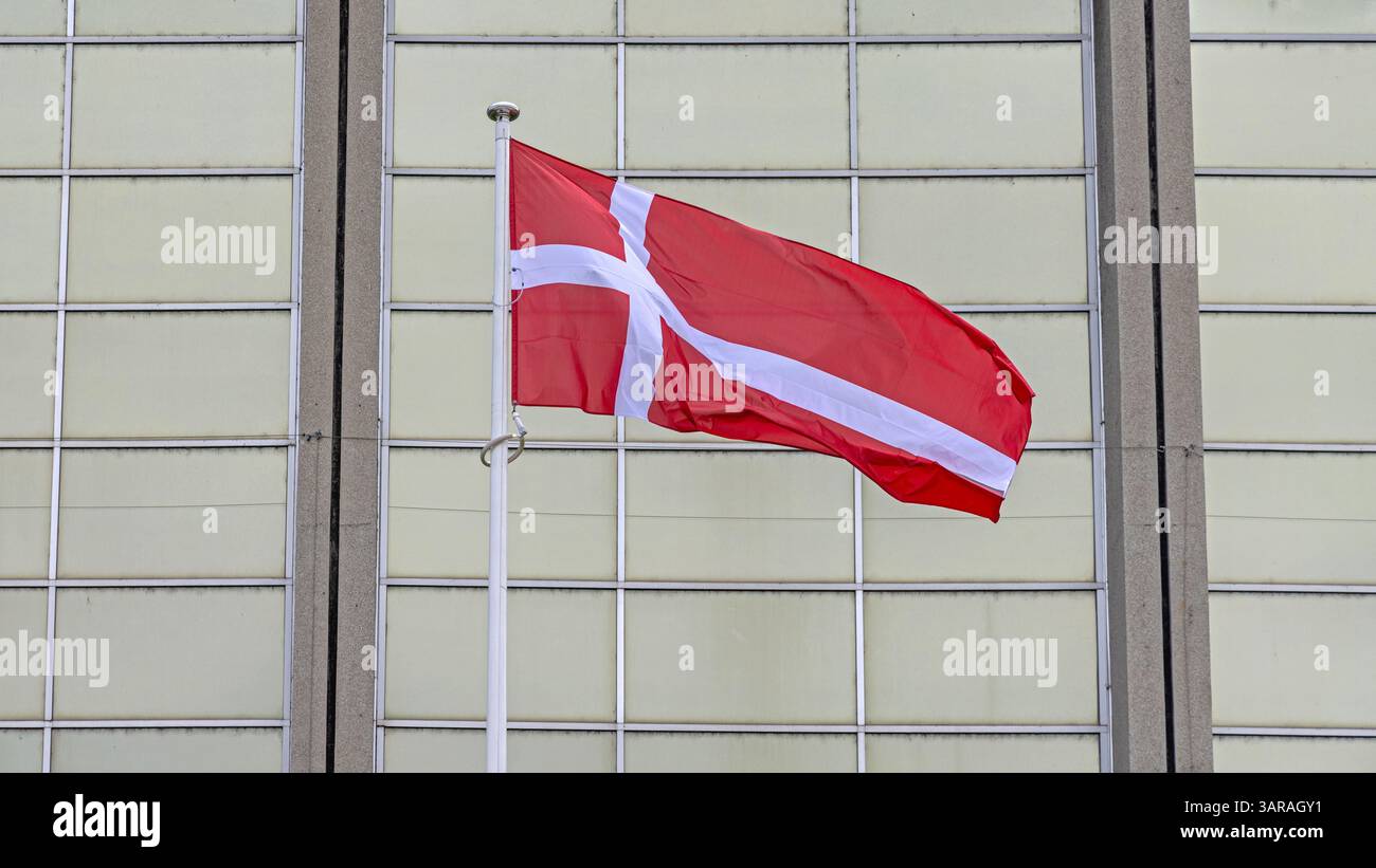 Älteste Flagge des Weltreichs Dänemark vor dem Glasgebäude Stockfoto