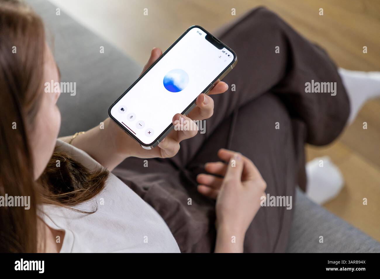 Posen, Polen – 14. April 2025: Eine junge Frau interagiert mit einem Smartphone mit einem GPT-basierten Sprachassistenten und demonstriert moderne KI-Technologie in e Stockfoto
