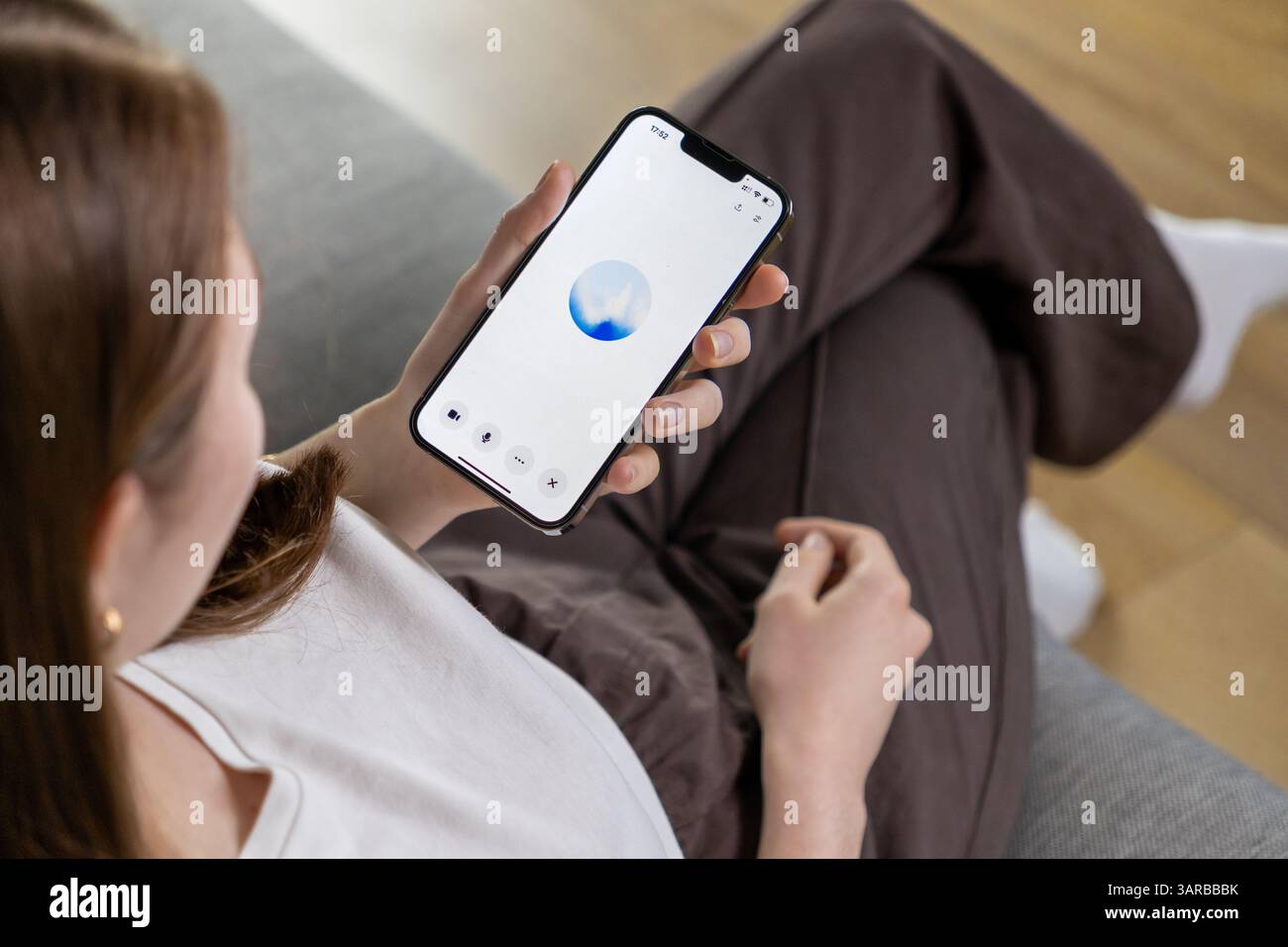 Posen, Polen – 14. April 2025: Eine Frau interagiert mit einer KI-Assistentin durch Spracheingabe auf ihrem Telefon und zeigt einen blauen animierten Kreis auf einem Minim Stockfoto