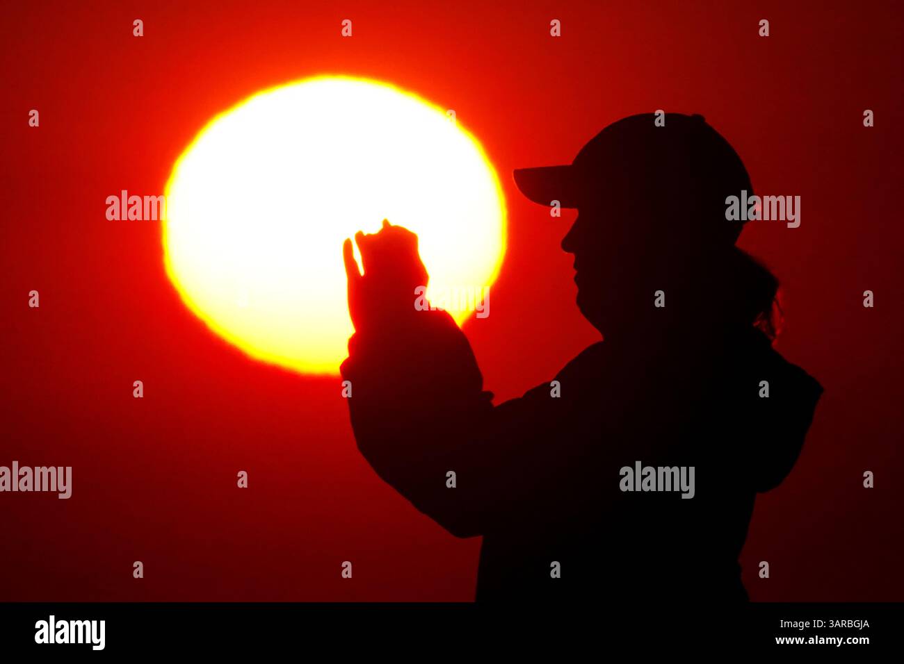Isle Of Palms, Usa. April 2025. Ein Fotograf mit der Silhouette des Sonnenaufgangs macht Fotos, während die Sonne am Strand des Wild Dunes Resort am 17. April 2025 in Isle of Palms, South Carolina, über den Horizont steigt. Quelle: Richard Ellis/Richard Ellis/Alamy Live News Stockfoto