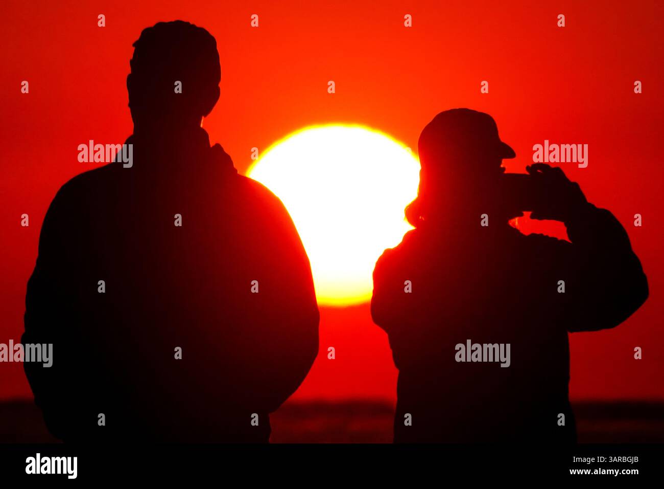 Isle Of Palms, Usa. April 2025. Ein Fotograf mit der Silhouette des Sonnenaufgangs macht Fotos, während die Sonne am Strand des Wild Dunes Resort am 17. April 2025 in Isle of Palms, South Carolina, aufgeht. Quelle: Richard Ellis/Richard Ellis/Alamy Live News Stockfoto