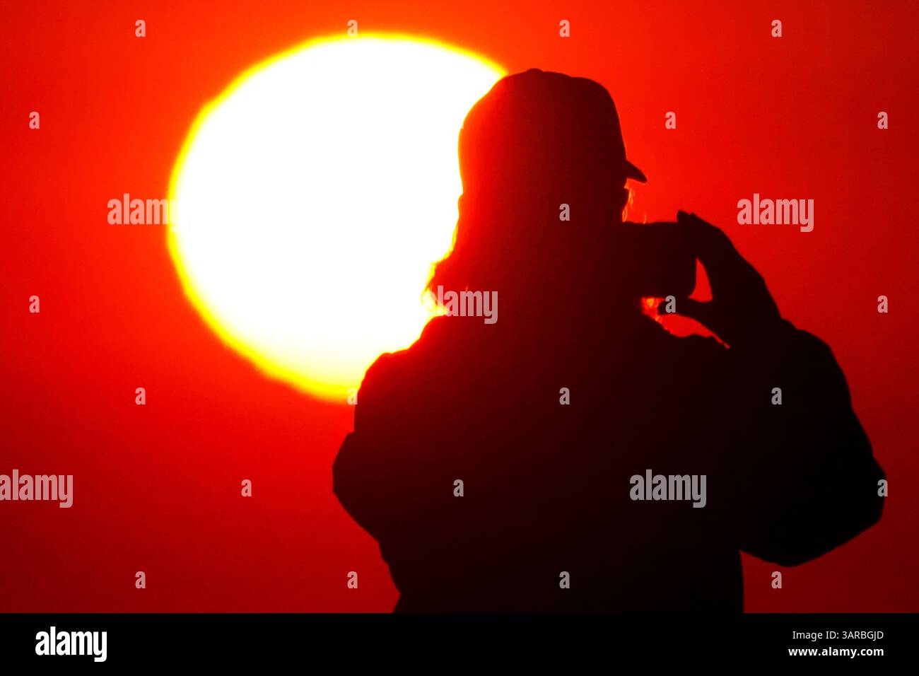 Isle Of Palms, Usa. April 2025. Ein Fotograf mit der Silhouette des Sonnenaufgangs macht Fotos, während die Sonne am Strand des Wild Dunes Resort am 17. April 2025 in Isle of Palms, South Carolina, über den Horizont steigt. Quelle: Richard Ellis/Richard Ellis/Alamy Live News Stockfoto