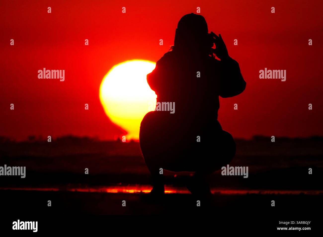 Isle Of Palms, Usa. April 2025. Ein Fotograf mit der Silhouette des Sonnenaufgangs macht Fotos, während die Sonne am Strand des Wild Dunes Resort am 17. April 2025 in Isle of Palms, South Carolina, über den Horizont steigt. Quelle: Richard Ellis/Richard Ellis/Alamy Live News Stockfoto