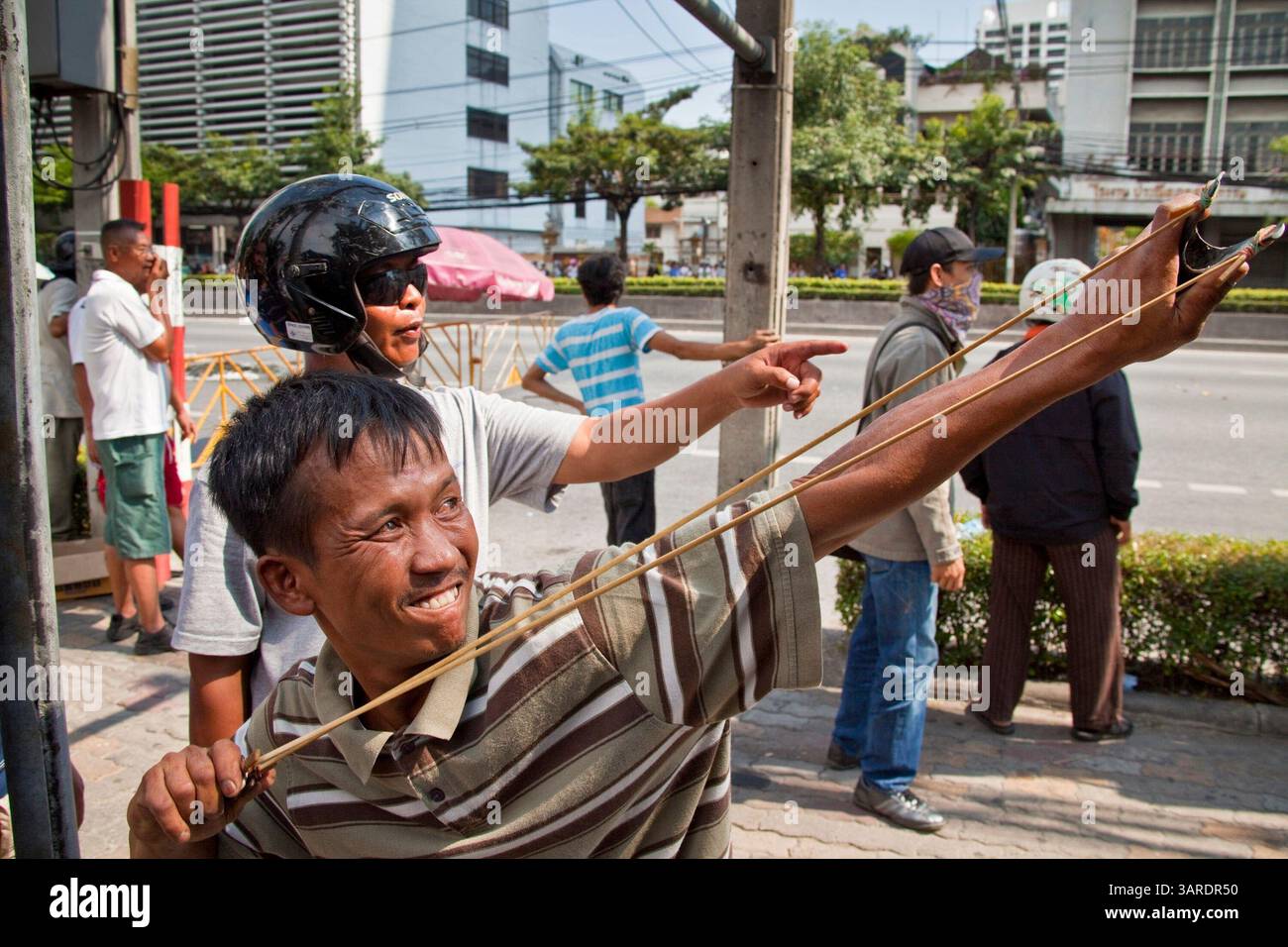 14. Mai 2010 - Bangkok, Thailand - Thailänder feuern mit Schleudern Steine und kleine selbstgemachte Sprengstoffe, die als Ping-Pong-Bomben bezeichnet werden, auf thailändische Truppen auf der Rama IV Rd. Ab Die thailändischen Sicherheitskräfte haben Live-Patronen abgefeuert, nachdem sie ein schwer verteidigtes Demonstrantenlager in Bangkok wegen Zusammenstößen, bei denen zwei Menschen getötet wurden, versiegeln wollten. Botschaften wurden geschlossen, als Demonstranten einen Polizeibus in Brand setzten und Feuerwerke auf Truppen schossen, die auch mit Tränengas und Gummigeschossen reagierten. Die Demonstranten wollen, dass der Premierminister zurücktritt und Wahlen ausruft. Viele der sogenannten Red-Shirt-Demonstranten unterstützen den ehemaligen Prime Mini Stockfoto