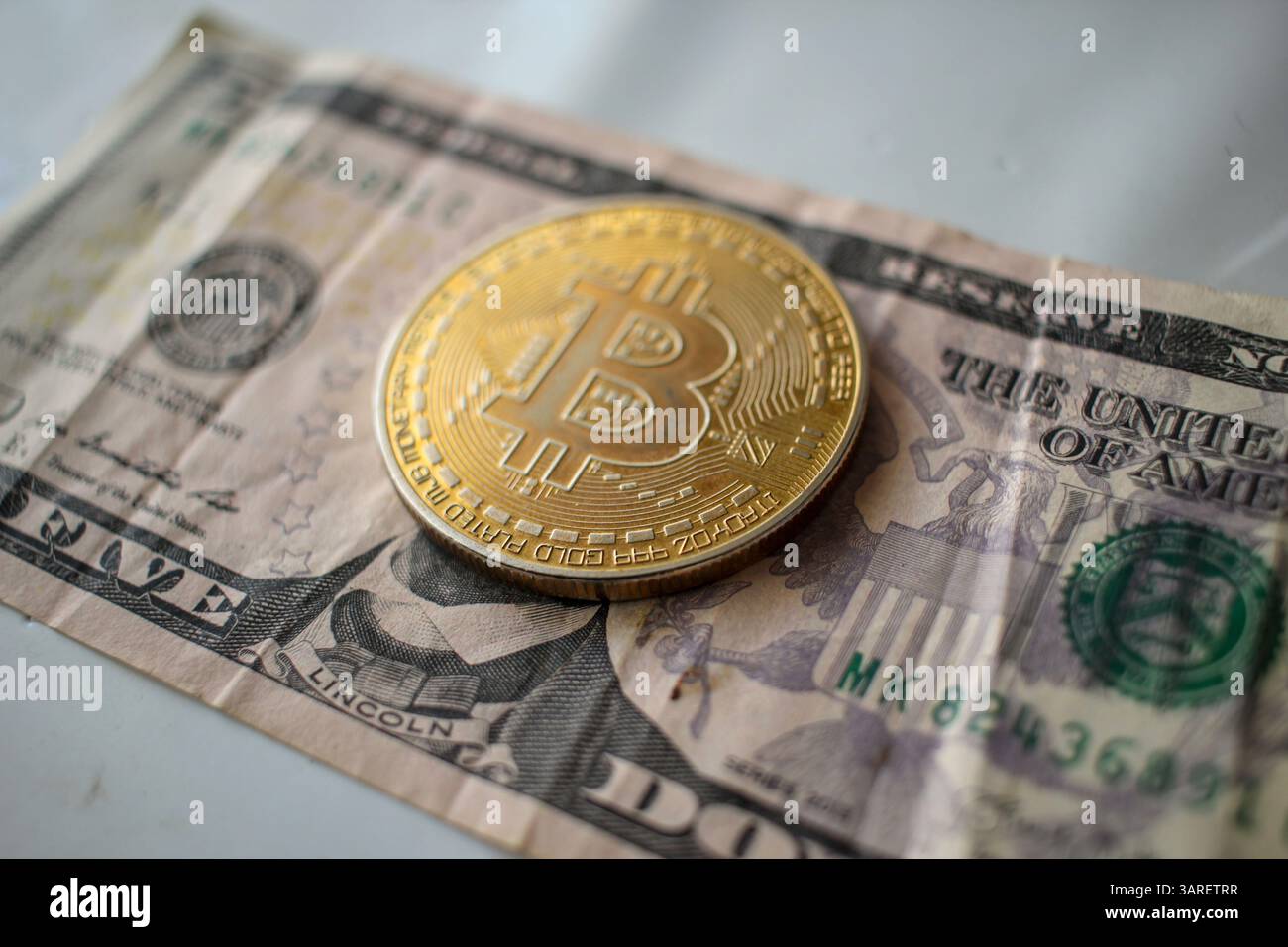 Der Kampf zwischen Dollar und Bitcoin auf einem 5-Dollar-Schein Stockfoto