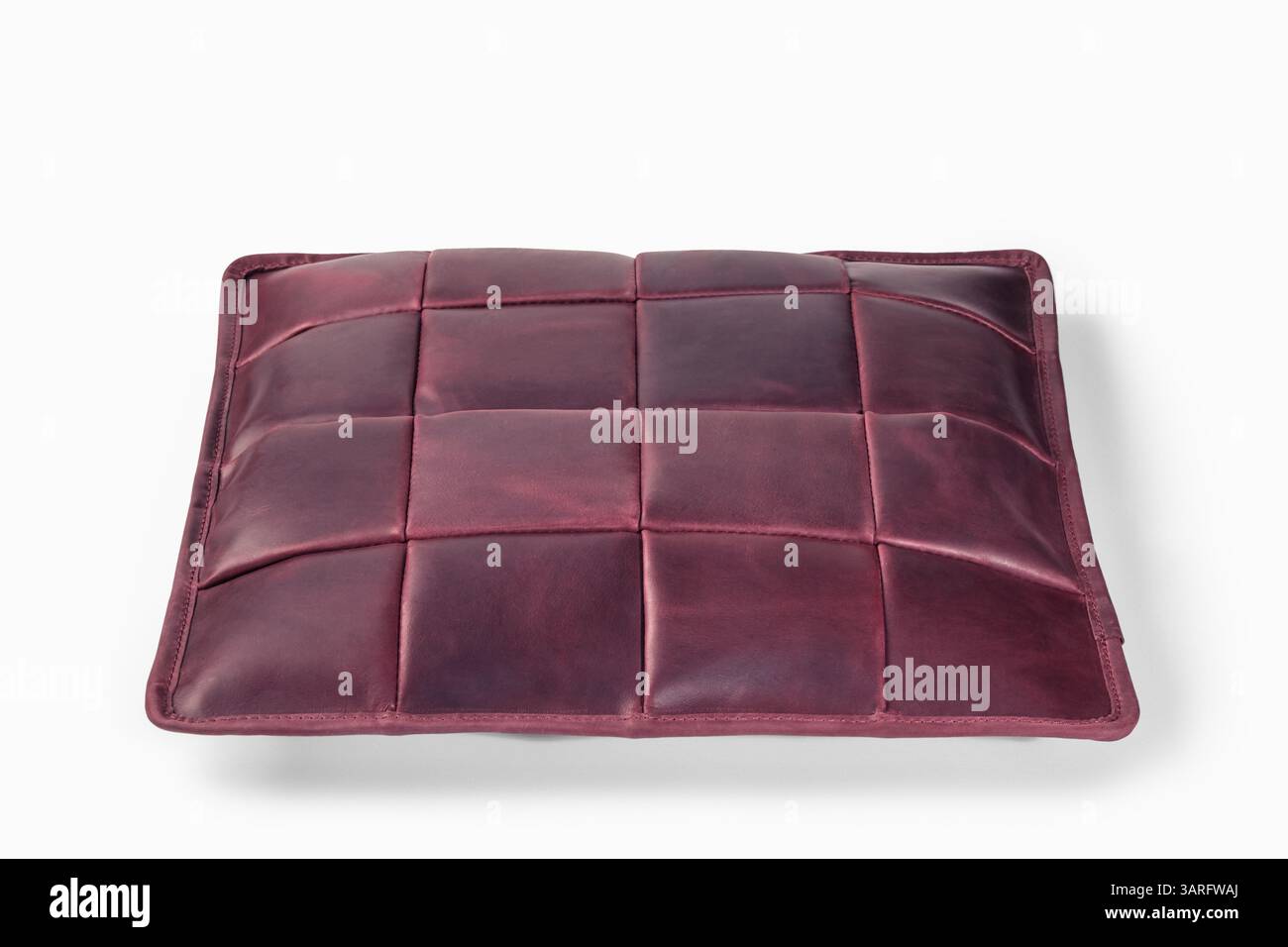 Burgunderfarbenes Lederkissen, das auf weißem Hintergrund schwebt: Moderne Inneneinrichtung Stockfoto