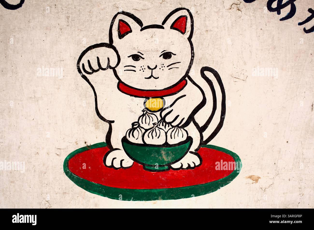 Maneki-neko-Katze mit einer Schüssel Momos von einem japanisch inspirierten Café-Schild, das ostasiatische Ikonographie mit Himalaya-Motiven verbindet. Stockfoto