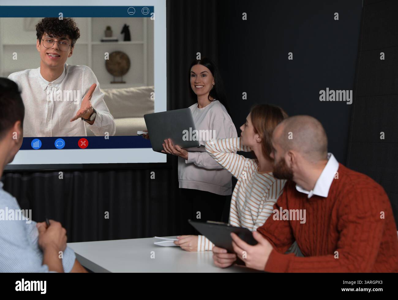 Redner, der über Online-Videochat an der Vorlesung teilnimmt. Publikum und Trainer im Konferenzraum mit Projektionsleinwand Stockfoto