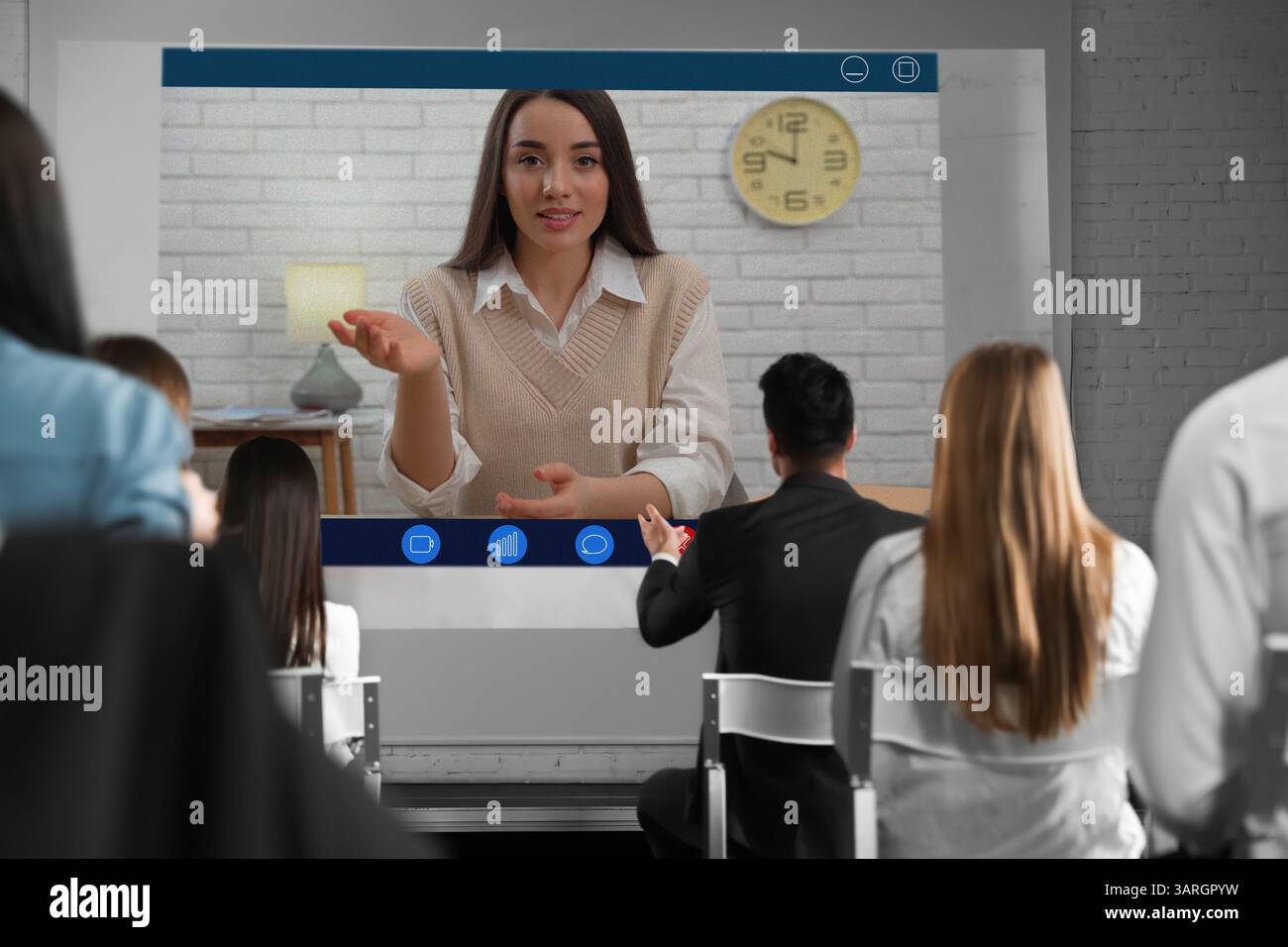 Redner, der über Online-Videochat an der Vorlesung teilnimmt. Publikum im Konferenzraum mit Projektionsleinwand Stockfoto